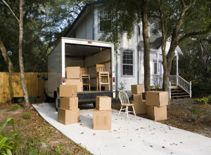 Moving van with cardboard box and chairs by house